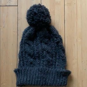 Dark gray winter knitted hat with puff ball.